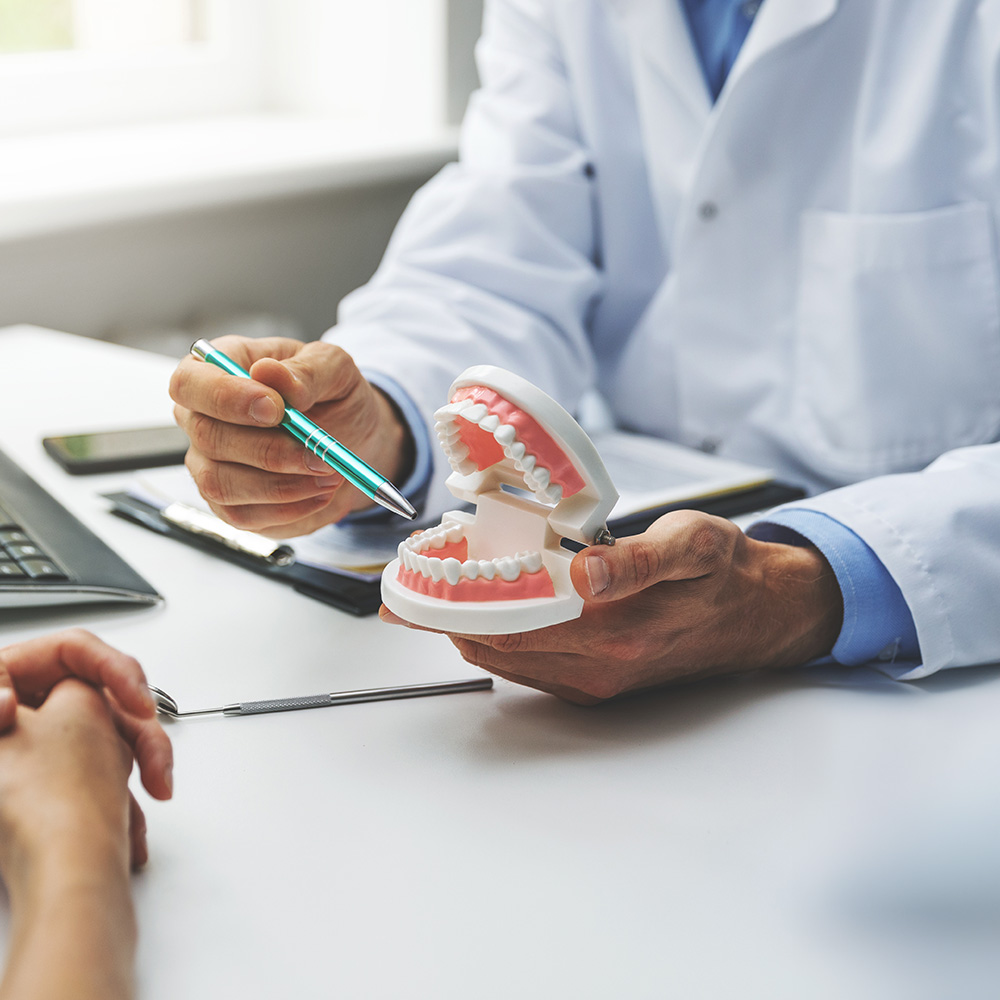 The image depicts a dental professional conducting an examination on a patient s teeth using a model set against a backdrop of a medical office environment, with the professional holding a pen and a smartphone.